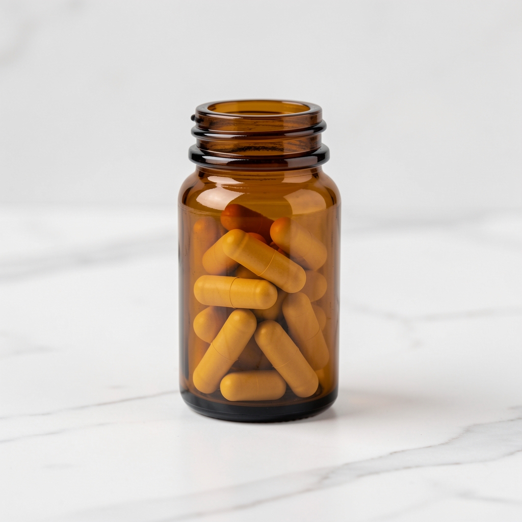 Small amber glass supplement bottle with capsules visible through the glass, placed on a white marble surface with clean studio lighting