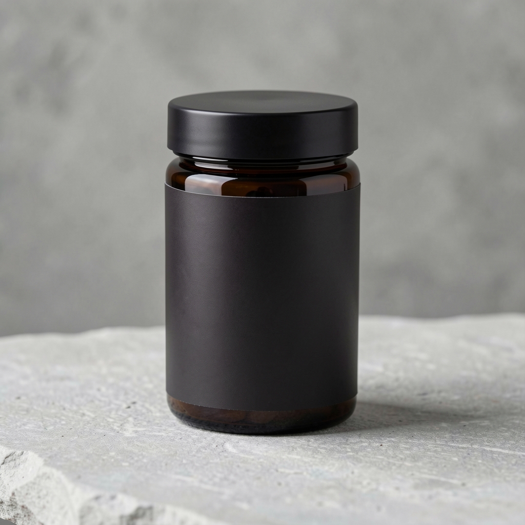 Dark cylindrical vitamin jar with a simple typographic label standing on a light grey stone surface photographed from three-quarter angle